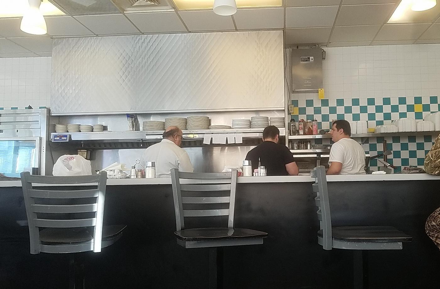 The counter at John's, looking through to the cook line and the teal and white checkered tile