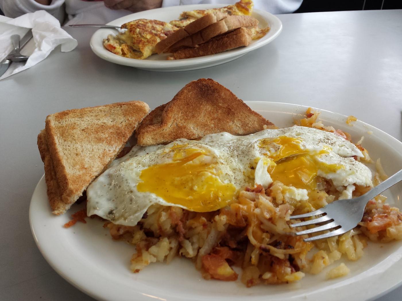 Two eggs over easy on loaded hash browns with buttered toast