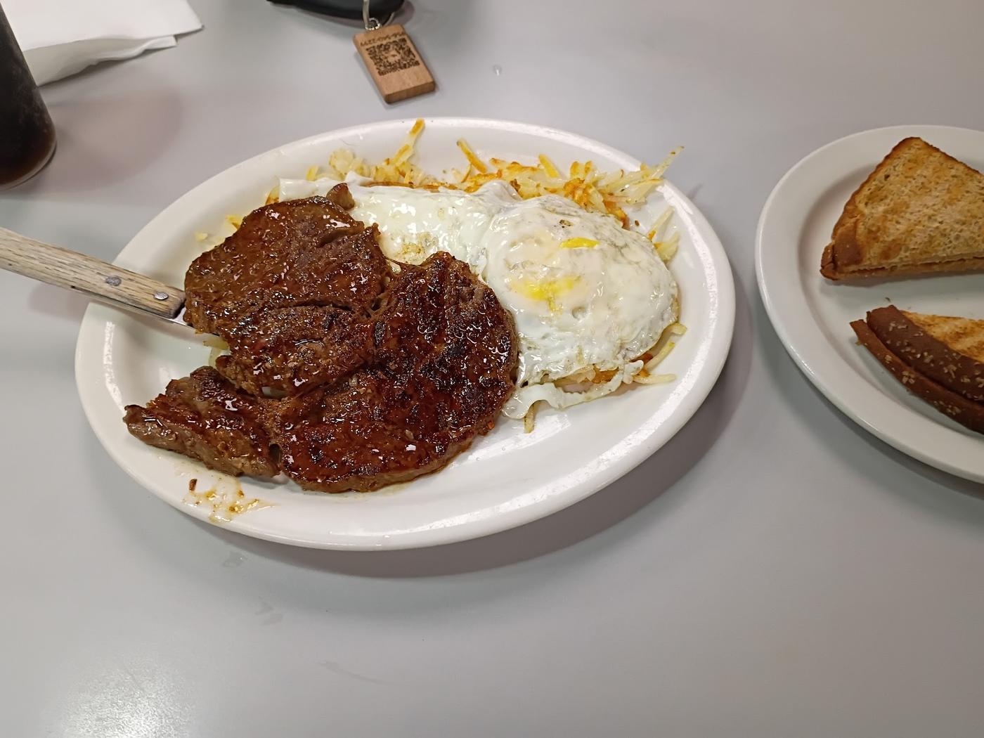 Ribeye with a fried egg and hash browns, toast on the side